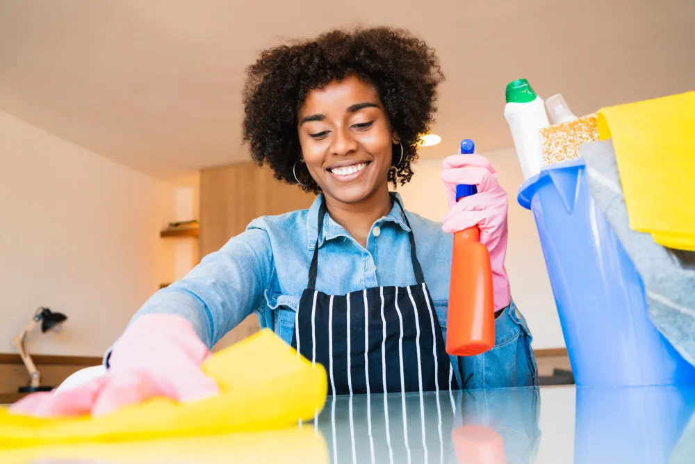 Cleaning professional wiping a counter beside cleaning supplies